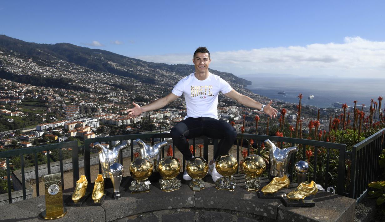 Bintang Real Madrid, Cristiano Ronaldo, berpose di depan trofi di kampung halamannya di Madeira, Portugal, Senin (1/1/2018). Pemain bernomor punggung tujuh itu memamerkan 15 trofi individual yang ia raih sebagai pemain terbaik. (AP/CR7 Media)