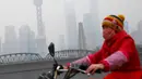Warga mengenakan masker saat bersepeda melintasi jalanan Shanghai yang masih diselimuti kabut asap tebal, Cina, 2 Januari 2017. (REUTERS/Aly Song)