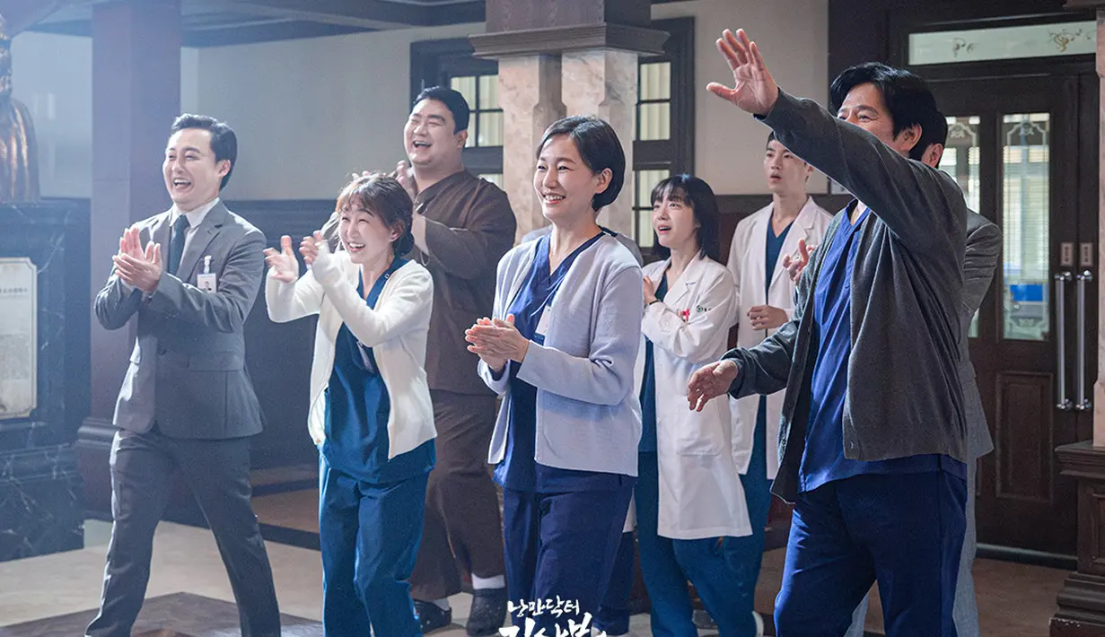 Dalam potongan gambar terbaru yang dirilis oleh SBS, tampak kehadiran Kang Dong Joo sang dokter bedah umum yang disambut hangat oleh keluarga besar rumah sakit Doldam. Mereka tersenyum dengan mata berbinar. (Foto: SBS via Soompi)