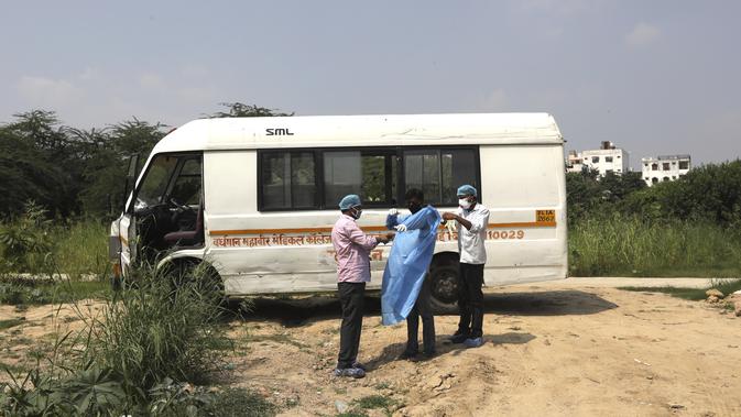 Petugas kesehatan membantu seorang pria mengenakan pakaian pelindung diri saat akan menguburkan putranya yang meninggal akibat COVID-19 di New Delhi (16/9/2020). Otoritas India melaporkan bahwa total kasus virus Corona (COVID-19) di wilayahnya telah melampaui 5 juta. (AP Photo/Manish Swarup)
