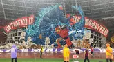 Koreografi raksasa dari suporter La Grande bergambar raksasa bergambarkan pertarungan antara Gundala dan Godzilla, serta tulisan "Untungnya Ku Tak Pilih Menyerah" di sisi kiri dan kanannya saat laga lanjutan putaran ketiga Grup C Kualifikasi Piala Dunia 2026 antara Timnas Indonesia melawan Jepang di Stadion Utama Gelora Bung Karno (SUGBK), Senayan, Jakarta, Jumat (15/11/2024). (Bola.com/Bagaskara Lazuardi)