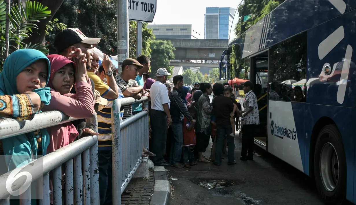 Petugas bus tingkat City Tour Wisata gratis mengatur warga yang hendak menaiki bus di halte Masjid Istiqlal, Jakarta, Kamis (7/7). Warga memanfaatkan fasilitas bus wisata gratis untuk berkeliling Jakarta bersama keluarga. (Liputan6.com/Yoppy Renato)