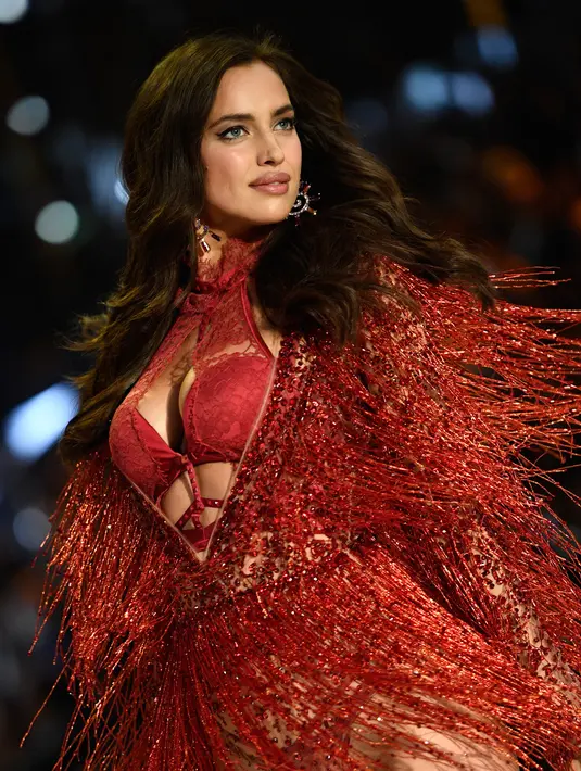 Model asal Rusia, Irina Shayk tampil percaya diri mengenakan lingerie merah dalam fashion show Victoria's Secret di Paris, Rabu (30/11).  Irina berusaha menutupi perut buncitnya di atas catwalk pagelaran pakaian dalam ternama tersebut. (Martin BUREAU/AFP)
