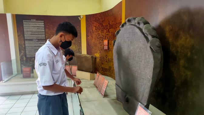 Dua orang pelajar di Palembang melihat arca peninggalan Kerajaan Sriwijaya, yang menjadi koleksi di Museum Negeri Sumsel (Liputan6.com / Nefri Inge)