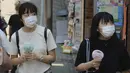 Dua wanita memakai masker wajah untuk membantu melindungi dari penyebaran coronavirus memegang kipas angin portabel untuk menghindari panas di Tokyo, Rabu, (5/8/2020). (AP Photo/Koji Sasahara)