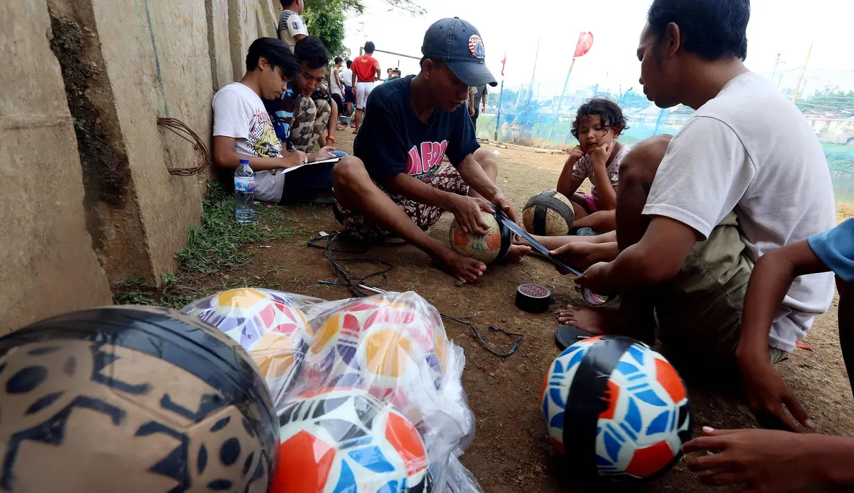 Warga menyiapkan bola untuk bermain dalam kompetisi sepak bola di pinggir Kali Banjir Kanal Barat, Jakarta, Sabtu (5/11). Minimnya sarana bermain sepak bola mengakibatkan warga terpaksa memanfaatkan lahan di pinggir kali. (Liputan6.com/Johan Tallo)