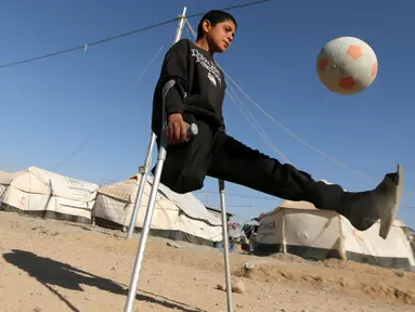 Seorang bocah bernama Jasim Abudllah bermain bola di kamp Debaga, di pinggiran Erbil, Irak (24/11). Meski hidup dengan satu kaki akibat terkena serangan udara, Jasim berusaha hidup seperti bocah normal lainya. (Reuters/Mohammed Salem)