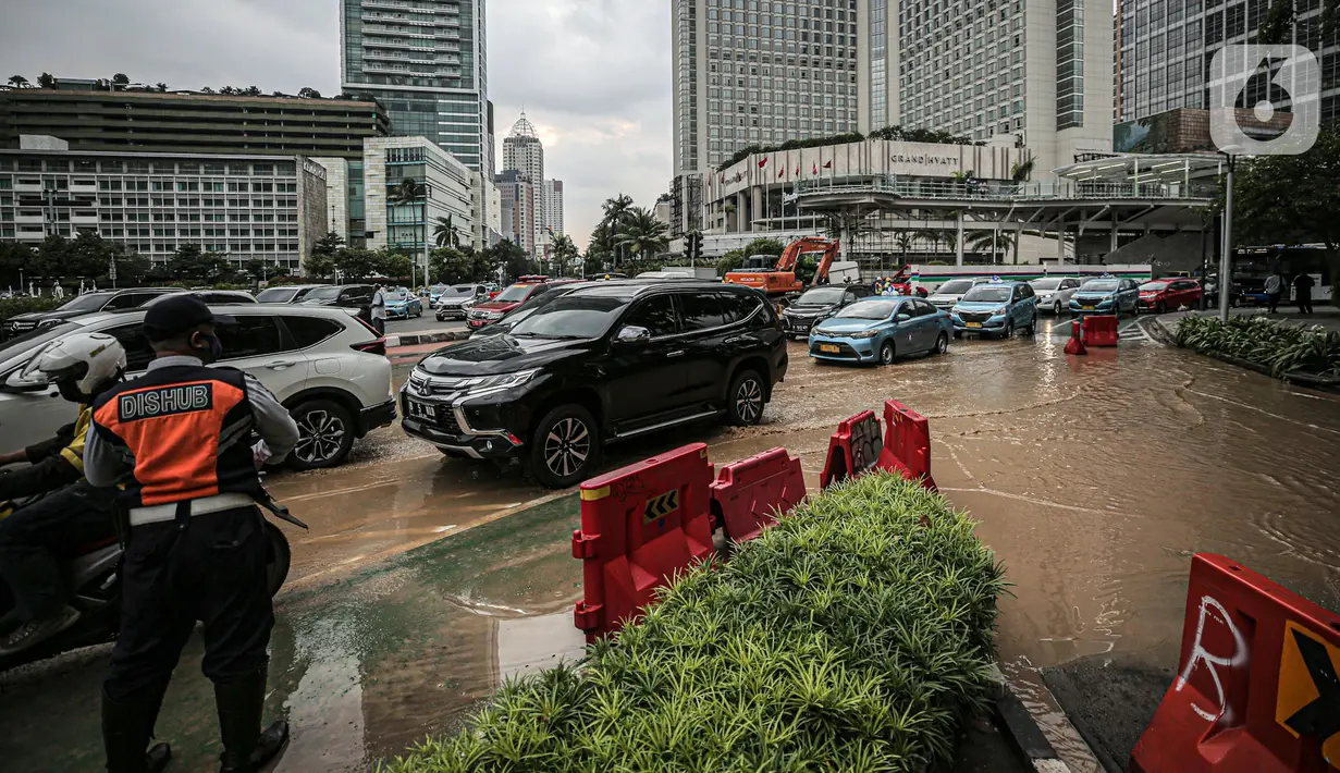 Petugas Dinas Perhubungan mengatur lalu lintas saat terjadi genangan air akibat kebocoran saluran pipa air di kawasan Bundaran Hotel Indonesia (HI), Jakarta, Selasa (11/10/2022). Kebocoran pipa air diduga terimbas proyek revitalisasi Halte Bundaran Hotel Indonesia. (Liputan6.com/Faizal Fanani)