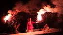 Sejumlah orang berada di atas kapal sambil menyalakan suar bersiap membakar patung Yudas saat perayaan tradisi Paskah kuno di semenanjung Peloponnese, Yunani (8/4). (AP/Petros Giannakouris)