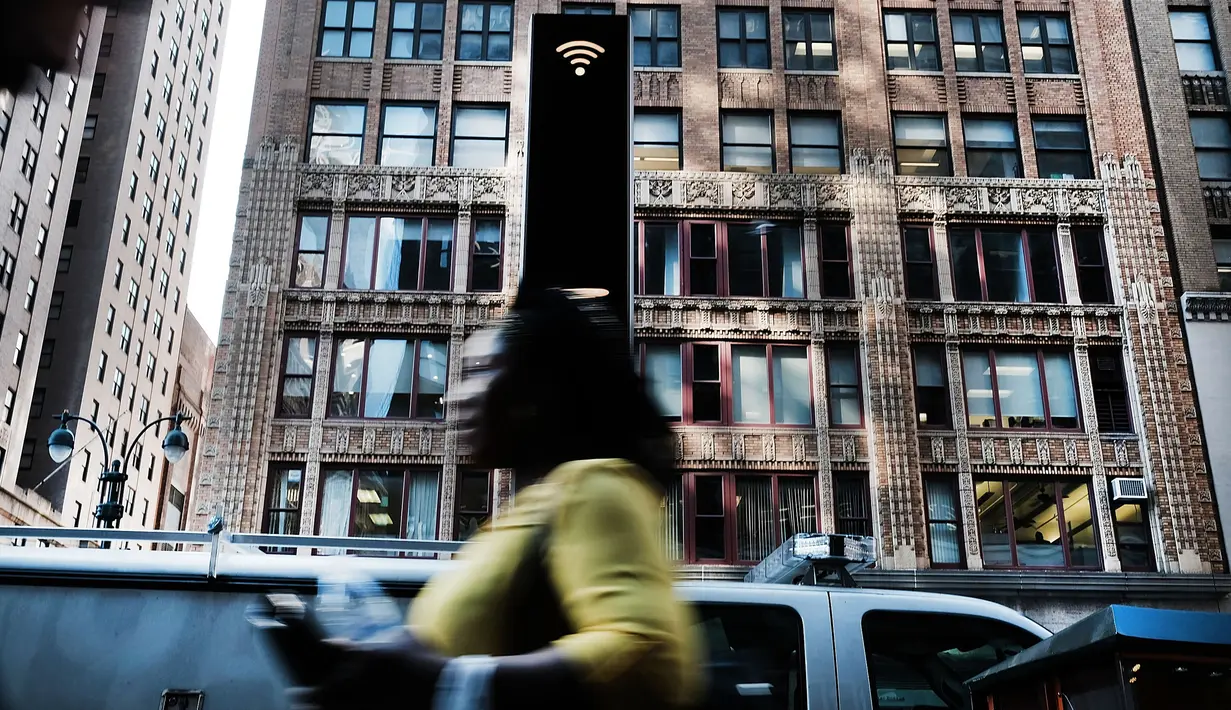 Pejalan kaki melewati salah satu kios Wi-Fi gratis di Manhattan, New York, 24 Agustus 2016. Proyek LinkNYC ini menyulap sejumlah telepon umum usang menjadi kios Wi-Fi gratis untuk bisa mengakses internet, menelepon dan pengisian baterai ponsel. (AFP)