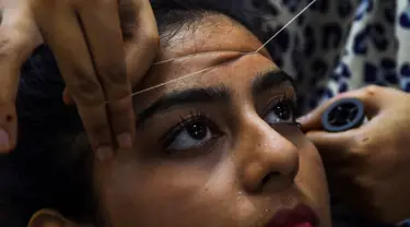 Seorang wanita Pakistan membersihkan rambut di wajah di salon kecantikan menjelang  Hari Raya Idul Fitri di Karachi (3/6/2019). Umat Muslim di seluruh dunia sedang bersiap untuk merayakan Hari Raya Idul Fitri, yang menandai akhir bulan puasa Ramadan. (AFP Photo/Asif Hassan)