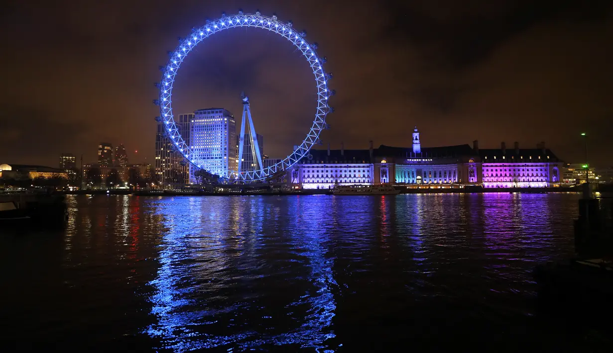 London Eye di tepi Sungai Thames diterangi dengan lampu biru untuk berterima kasih kepada National Health Service (NHS) di London, Kamis (7/1/2021). NHS merupakan sistem layanan kesehatan nasional yang menjadi ujung tombak Inggris dalam memerangi pandemi Covid-19. (AP Photo/Kirsty Wigglesworth)