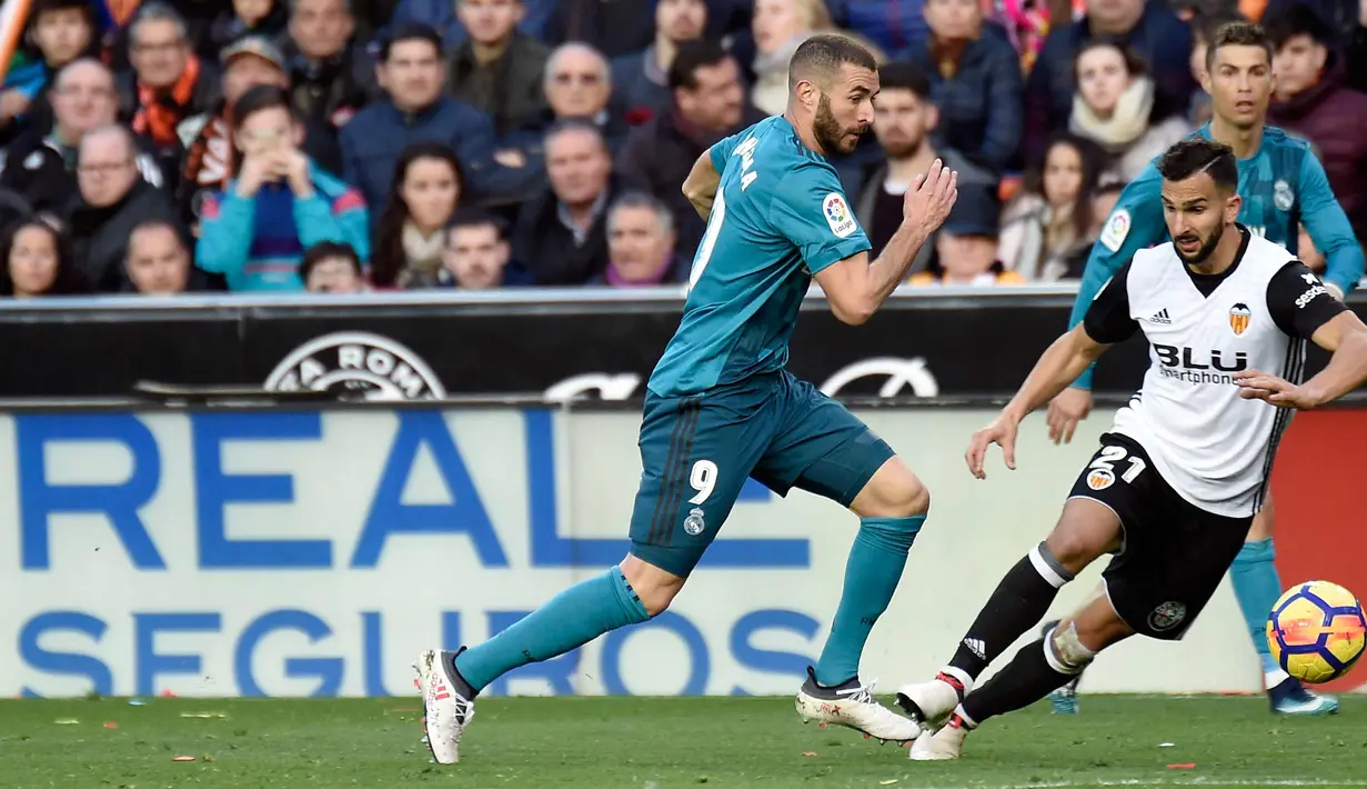 Penyerang Real Madrid, Karim Benzema berusaha mengejar bola dari kawalan bek Valencia, Martin Montoya saat bertanding pada lanjutan La Liga Spanyol di stadion Mestalla, (27/1). Real Madrid menang 4-1. (AFP Photo/Jose Jordan)