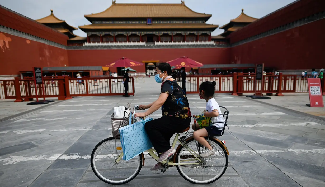 <p>Seorang perempuan mengendarai sepedanya dengan seorang anak duduk di kursi belakang melewati Kota Terlarang di Beijing, China, Selasa (7/6/2022). Pemerintah melonggarkan beberapa pembatasan Covid-19 dengan sebagian besar museum gedung bioskop, dan pusat kebugaran diizinkan beroperasi hingga 75 persen dari kapasitas. (WANG Zhao / AFP)</p>