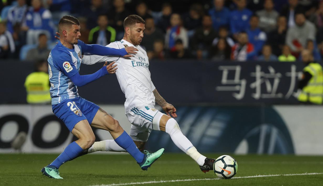 Pemain Real Madrid, Sergio Ramos mencoba melepaskan tembakan saat diadang pemain Malaga, Maxime Lestienne pada lanjutan La Liga Santander di Rosaleda stadium, Malaga, (15/4/2018). Madrid menang 2-1. (AP/Miguel Morenatti)