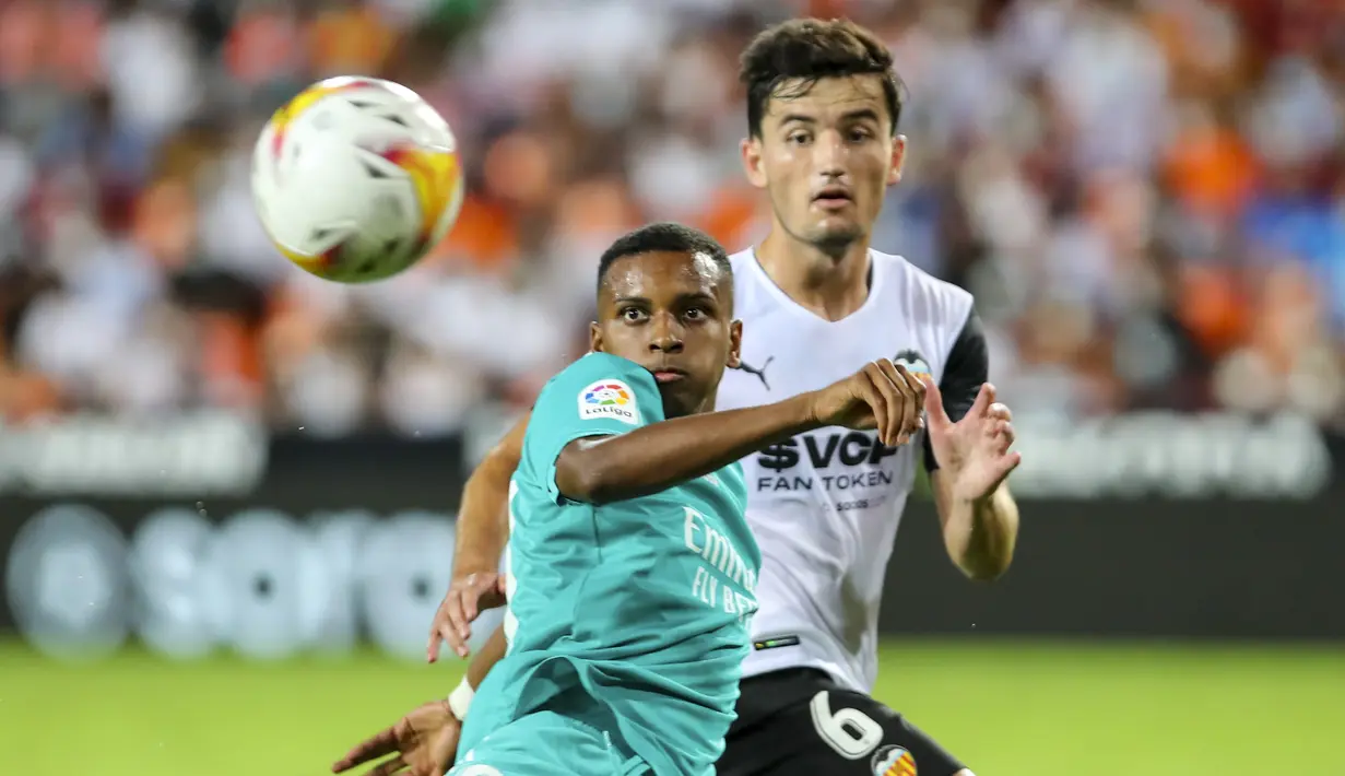 Penyerang Real Madrid, Rodrygo berebut bola dengan bek Valencia, Hugo Guillamon pada lanjutan La Liga di Stadion Mestalla, Senin (20/9/2021) dini hari WIB. Real Madrid menang 2-1 secara dramatis atas Valencia. (AP Photo/Alberto Saiz)