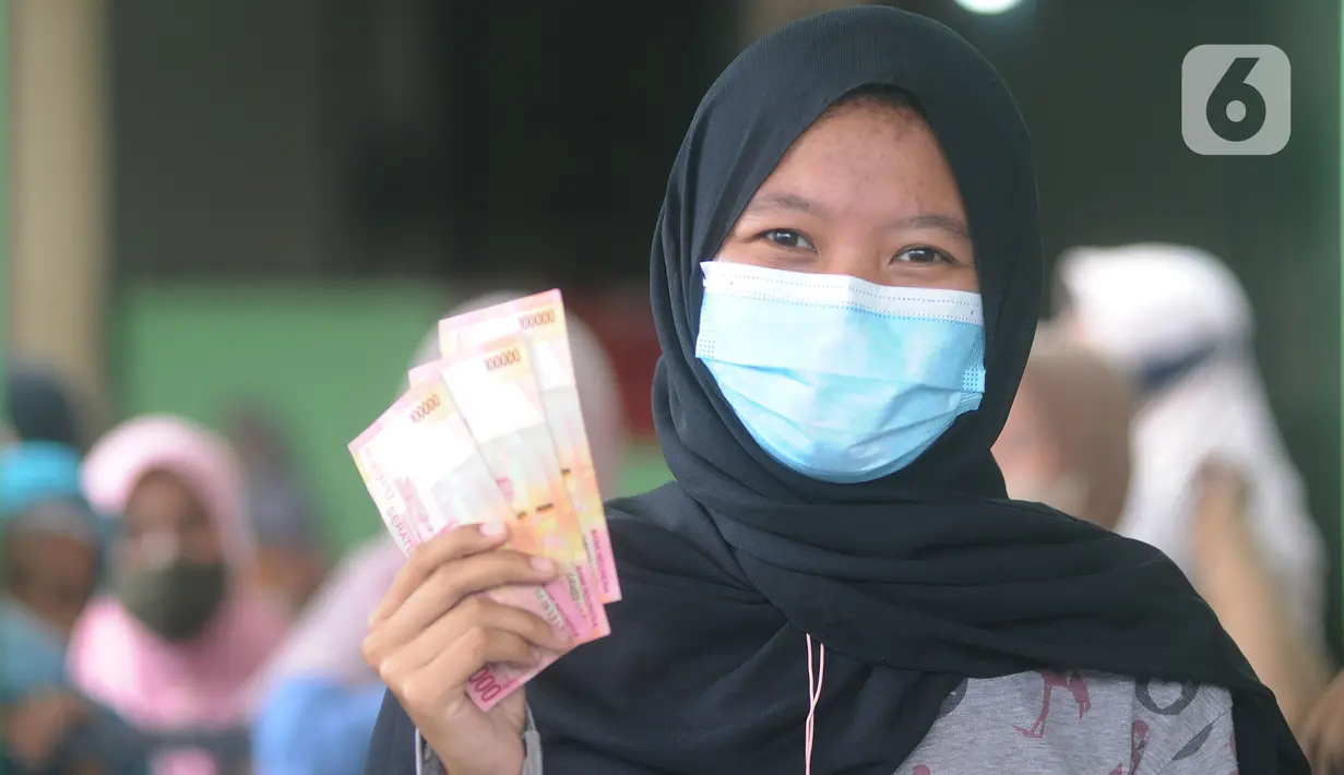 Warga penerima menunjukkan uang Bantuan Sosial Tunai (BST) bulan Januari di halaman Masjid Jami Al-Hidayah RW 01 Bedahan, Depok, Selasa (16/2/2021). Sekitar 159.470 Keluarga Penerima Manfaat (KPM) di Kota Depok menerima BST yang disalurkan PT Pos Indonesia pada Februari ini (merdeka.com/Arie Basuki)