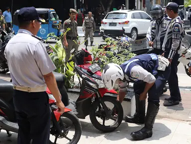 Petugas mengempeskan ban motor saat melakukan penertiban di kawasan pusat perbelanjaan Pasar Baru, Jakarta, Rabu (21/2). Penertiban dilakukan oleh petugas gabungan dari Satpol PP dan Dinas Perhubungan, serta Pasukan Oranye.(Liputan6.com/Immanuel Antonius)