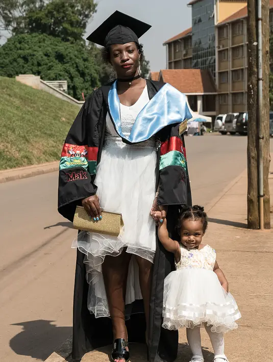 Seorang wisudati membawa anaknya untuk mengikuti upacara wisuda ke-68 di Universitas Makerere di Kampala, Uganda (19/1). Upacara wisuda tersebut diikuti lebih dari 14.000 mahasiswa. (AFP Photo/Michele Sibiloni)