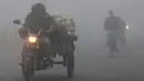 Pedagang sayur melintasi kabut tebal dan polusi udara di Amritsar, India (2/1). (AFP Photo/Narinder Nanu)