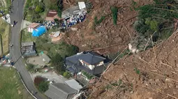 Petugas penyelamat dan polisi melakukan evakuasi di sekitar lokasi terjadinya longsor yang menghantam rumah hunian di Nakatsu, Prefektur Oita, Jepang (11/4). (Takuto Kaneko/Kyodo News via AP)
