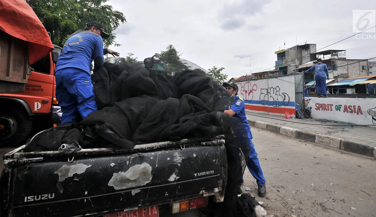 Petugas menata kain waring atau jaring ke atas mobil yang sebelumnya menutupi Kali Item di Kemayoran, Jakarta, Rabu (14/11). Pelepasan waring tersebut dilakukan lantaran banyak warga yang membuang sampah di atasnya (Merdeka.com/Iqbal S. Nugroho)