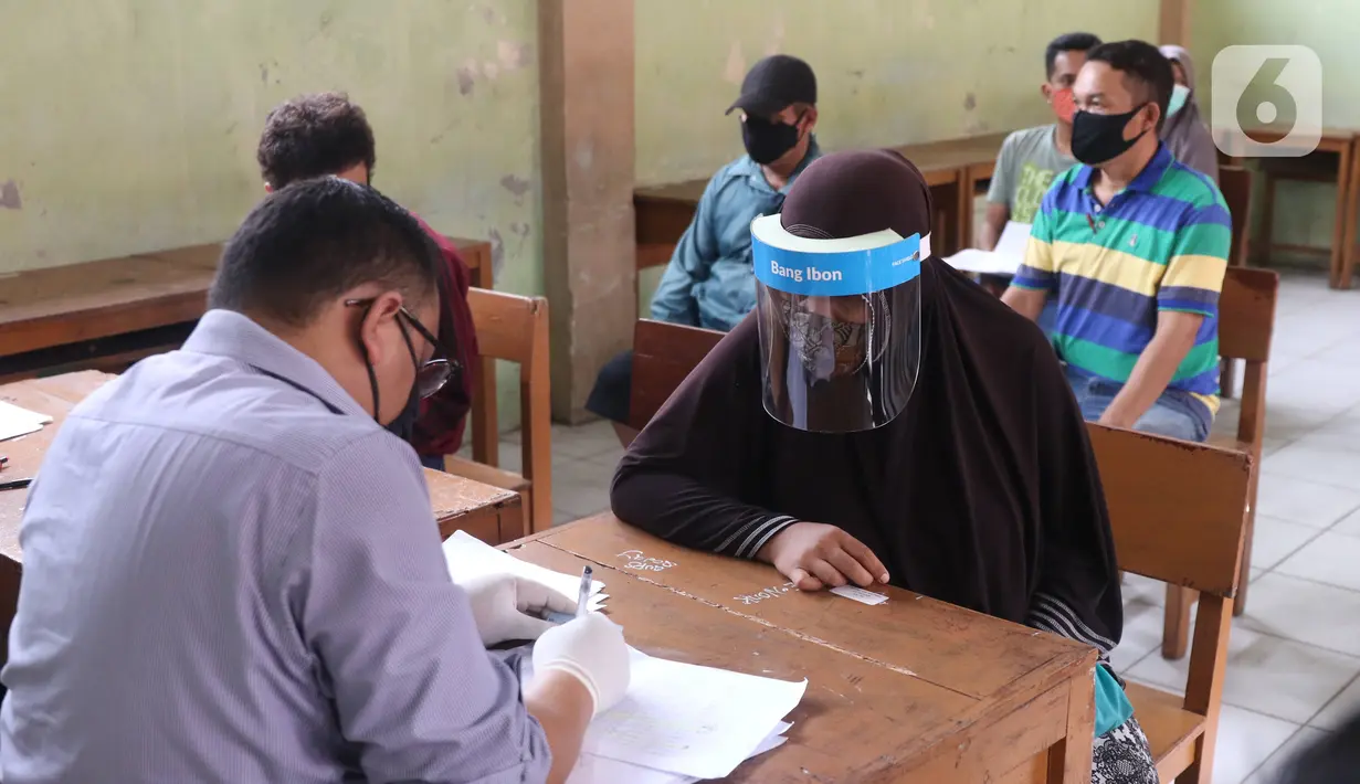 Petugas mendata warga saat pembagian bantuan sosial (bansos) yang diberikan Pemerintah Provinsi Banten di Pinang, Tangerang, Jumat (1/5/2020). Bansos berupa uang tunai sebesar Rp 600 ribu tersebut diberikan kepada warga yang terdampak virus corona COVID-19. (Liputan6.com/Angga Yuniar)