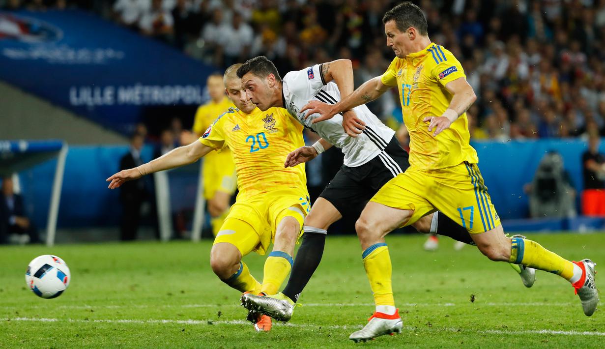 Gelandang Jerman, Mesut Ozil (tengah) berusaha melewati dua pemain Ukraina di kualifkasi grup C Piala Eropa 2016 di Stadion Stade Pierre-Mauroy, Perancis, (12/6). Jerman menang atas Ukraina dengan skor 2-0. (REUTERS/Gonzalo Fuentes)