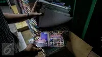 Petugas menunjukkan kaset bajakan saat melakukan razia di Plaza Glodok, Jakarta, Rabu (24/6). Razia dilakukan karena pabrik sekaligus tempat penjualan DVD terbesar di DKI Jakarta itu masih beroperasi selama Ramadan. (Liputan6.com/Faizal Fanani)