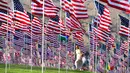 Seorang wanita dan anak melewati pameran bendera AS untuk peringatan 20 tahun serangan 9/11 di Pepperdine University di Malibu, Rabu (8/9/2021). Selama 14 tahun, universitas itu memperingati tragedi 11 September 2001 dengan mengibarkan sekitar 3.000 bendera Amerika. (Frederic J. BROWN/AFP)