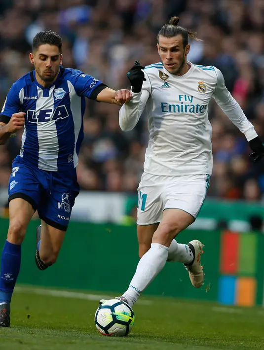 Penyerang Real Madrid, Gareth Bale berusaha melewati pemain Alaves, Ruben Sobrino saat bertanding pada lanjutan La Liga Spanyol di stadion Santiago Bernabeu (24/2). Madrid menang 4-0 atas Alaves. (AP Photo/Francisco Seco)