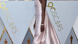 Aktris Danai Gurira berpose di karpet merah ajang Piala Oscar 2018, Los Angeles, Minggu (4/3).  Pemeran Okoye dalam film "Black Panther" ini tampil stunning dengan gaun merah muda sederhana beserta aksesori silver di tubuhnya. (VALERIE MACON / AFP)