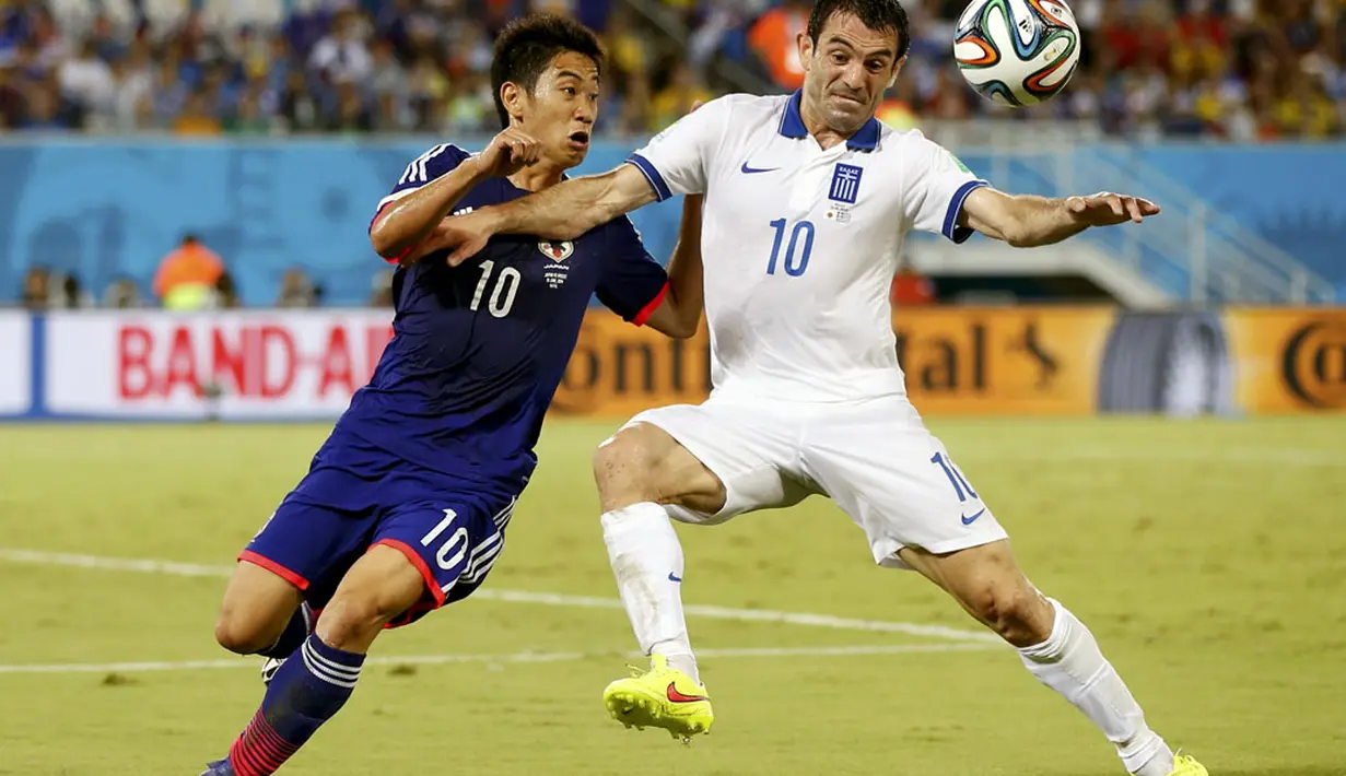 Gelandang Timnas Jepang, Shinji Kagawa (kiri), bertarung berebut bola dengan Giorgos Karagounis (Yunani) saat berlaga di babak penyisihan Piala Dunia 2014 Grup C di Stadion Dunas, Natal, Brasil, (20/6/2014). (REUTERS/Toru Hanai)