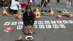 Salah satu petani Kendeng terduduk saat aksi di depan Istana Negara, Jakarta, Kamis (2/8). Dalam aksinya, petani Kendeng melakukan tradisi Brokohan atau makan bersama nasi aneka urap yang sebelumnya didoakan. (Liputan6.com/Helmi Fithriansyah)