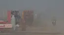 Seorang pedagang (tengah) menata kiosnya di pinggir jalan di tengah kondisi kabut asap tebal di Lahore, Pakistan, Kamis (18/11/2021). Tingkat kualitas udara di Lahore berada di angka 348, jauh di atas ambang batas berbahaya yaitu 300. (Arif ALI/AFP)