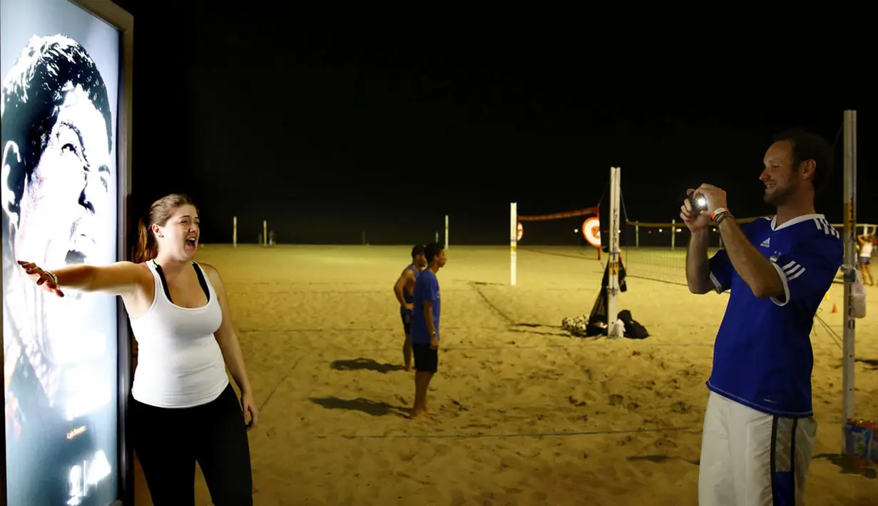 Neon box iklan bergambar Luis Suarez di pantai Copacabana, Rio de Janeiro, Brasil, mengundang pengunjung untuk mengekspresikan diri seolah-olah menjadi korban penggigitan, (26/6/2014). (REUTERS/Kai Pfaffenbach)