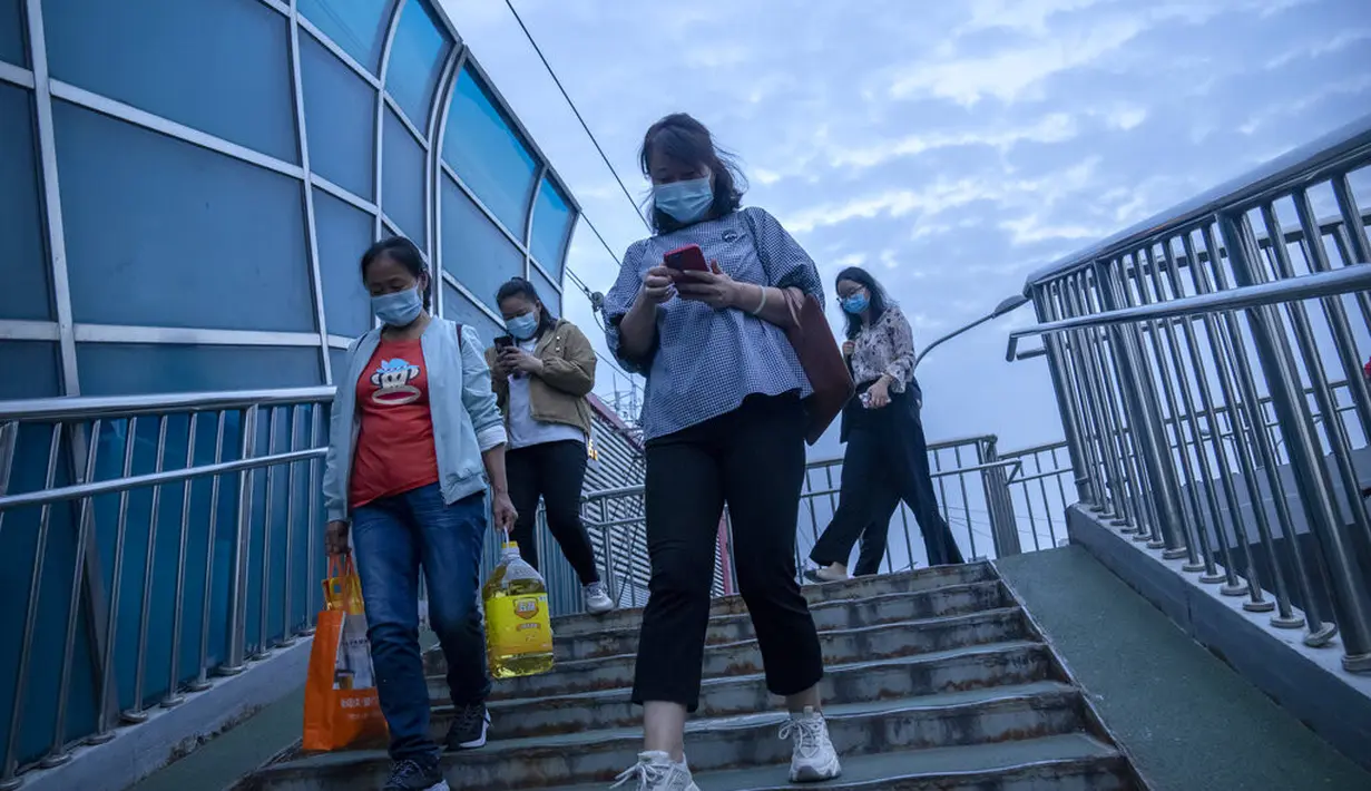 Orang-orang berjalan melintasi jembatan penyeberangan di lingkungan dengan dugaan kasus virus corona di Beijing (15/9/2021). China memperketat penguncian dan meningkatkan pesanan untuk pengujian massal di kota sepanjang pantai timurnya di tengah lonjakan kasus COVID-19. (AP Photo/Mark Schiefelbein)
