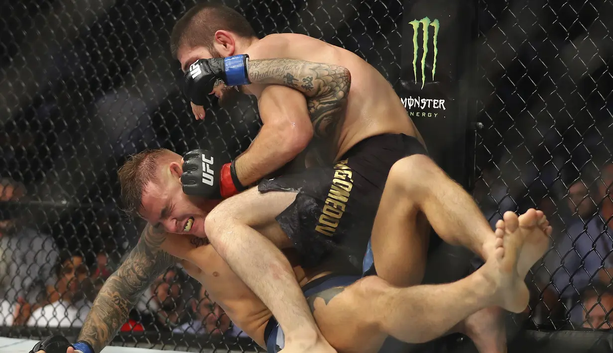 Khabib Nurmagomedov berusaha mengunci Dustin Poirier dalam pertarungan UFC 242 di Mal Yas di Abu Dhabi, Uni Emirat Arab (7/9/2019). habib sukses menang setelah kuncian lehernya memaksa Dustin melakukan tap out. (AP Photo/ Mahmoud Khaled)