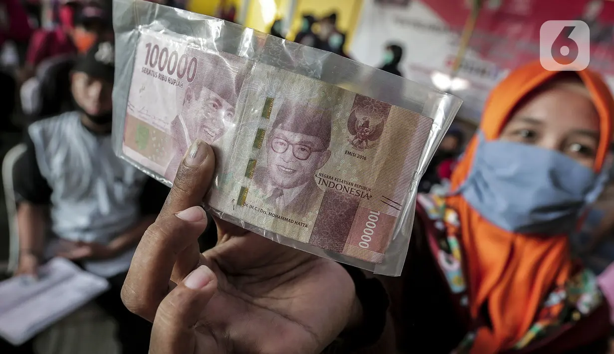 Warga menunjukkan uang tunai usai menerima Bantuan Sosial Tunai (BST) di Desa Cikande, Kecamatan Jayanti, Kabupaten Tangerang, Banten, Selasa (23/6/2020). Bantuan tersebut merupakan salah satu program jaring pengaman sosial terkait pandemi virus corona COVID-19. (Liputan6.com/Johan Tallo)