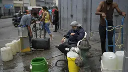 Warga memanfaatkan hidran kebakaran untuk mengisi wadah mereka dengan air di lingkungan San Juan di Caracas, Venezuela (19/1/2021). Venezuela merupakan negara dengan salah satu cadangan minyak terbesar di dunia. (AP Photo/Matias Delacroix)