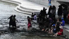 Warga bermain air saat siang hari di Sungai Cheonggye, Seoul, Korea Selatan, Senin (23/7). Korea Selatan tengah dilanda cuaca panas sepanjang pekan ini. (AP Photo/Lee Jin-man)