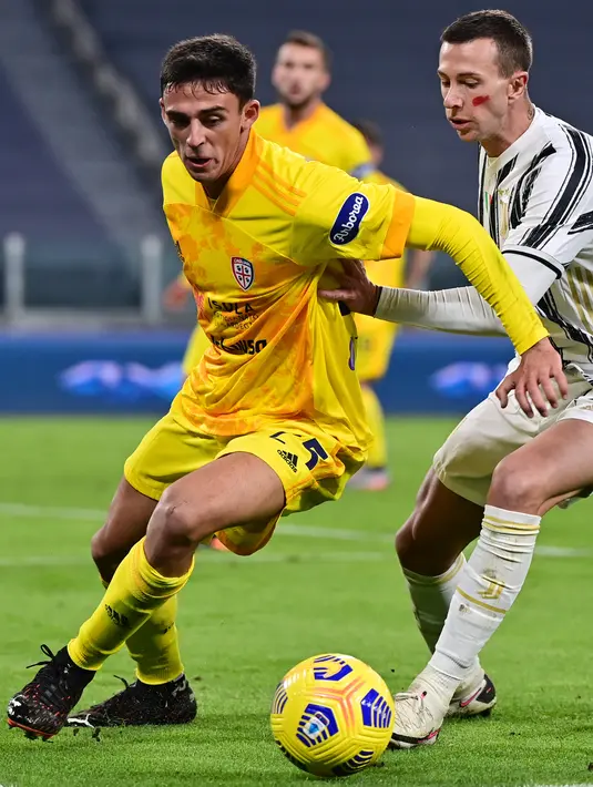 Penyerang Juventus, Federico Bernardeschi (kanan) berusaha merebut bola bek Cagliari, Gabriele Zappa selama pertandingan lanjutan Liga Serie A Italia di stadion Juventus di Turin (21/11/2020). Juventus menang atas Cagliari 2-0. (AFP/Miguel Medina)