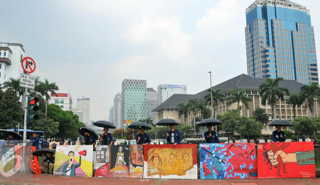 Sejumlah mahasiswa Trisakti menggelar aksi dengan memajang gambar mural bertema kemanusiaan di Bundaran Patung Kuda, Jakarta, Kamis (12/5). Aksi ini bertujuan untuk memperingati tragedi trisakti 12 Mei 98. (Liputan6.com/Yoppy Renato)