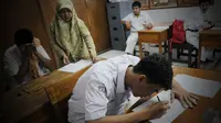 Seorang siswa Tuna Netra peserta Ujian Nasional tingkat SMA di SLB Negeri Beringin Purwakarta, Jawa Barat kemarin harus dibantu guru yang bisa membacakan huruf braile.