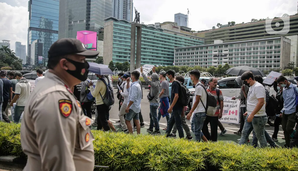 Ratusan imigran Afghanistan jalan kaki menuju Kedubes Kanada di Jakarta, Senin (13/12/2021). Dengan membawa spanduk dan poster, mereka menuntut UNHCR dan IOM segera memproses penempatan mereka ke negara tujuan seperti Kanada, Australia, Selandia Baru maupun AS. (Liputan6.com/Faizal Fanani)