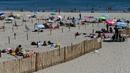 Orang-orang menikmati sore dengan area terpisah untuk mematuhi jaga jarak di pantai "Plage du Couchant" di La Grande-Motte, Prancis Selatan, Selasa (26/5/2020). Otoritas setempat membuat kotak-kotak yang dapat ditempati para pengunjung tetap bisa menjaga jarak fisik di pantai. (Pascal GUYOT/AFP)