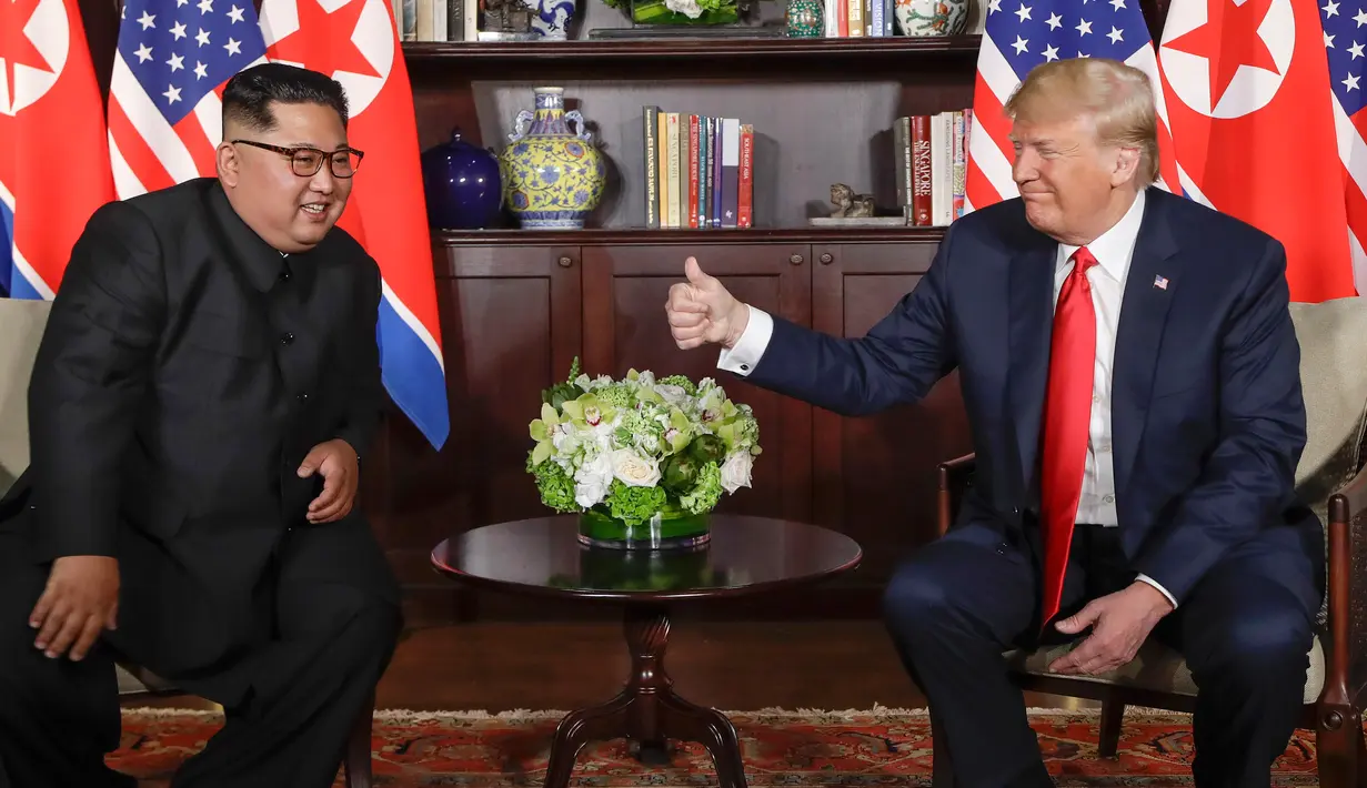 Presiden AS Donald Trump  memberikan jempolnya seusai berjabat tangan dengan Pemimpin Korea Utara, Kim Jong-un dalam pertemuan bersejarah di resor Capella, Pulau Sentosa, Selasa (12/6). Trump dan Kim saling melemparkan senyum. (AP/Evan Vucci)