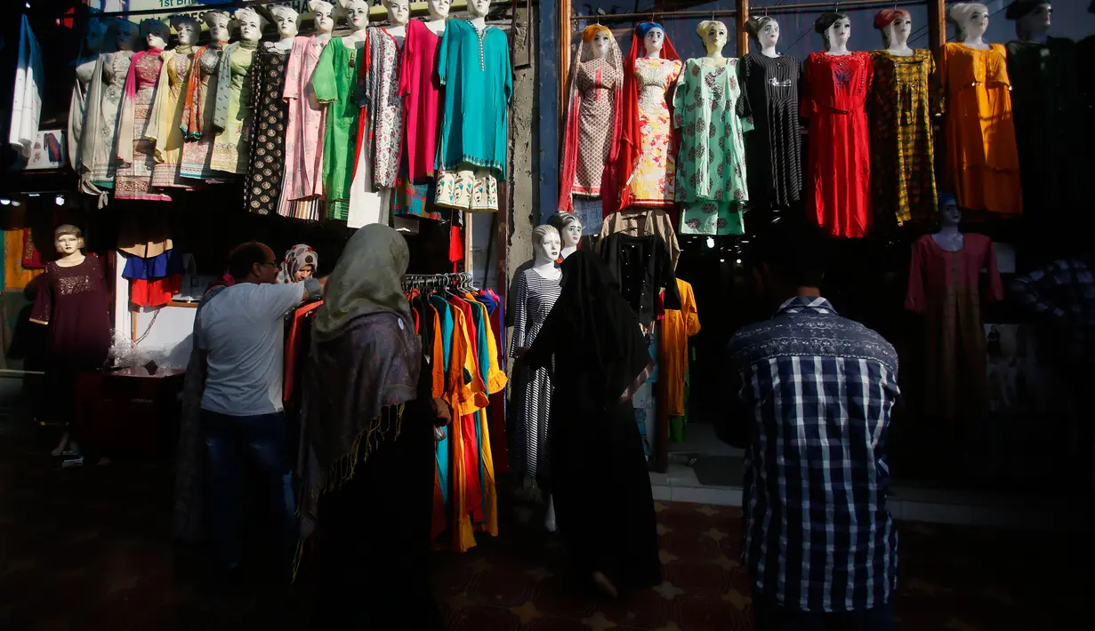 Dua wanita muslim Kashmir mencari pakaian sebelum Idul Fitri di Srinagar, Kashmir yang dikuasai India (2/6/2019). Idul Fitri, menandai berakhirnya bulan puasa Ramadan. (AP Photo/Mukhtar Khan)