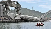 Tim penyelamat menggunakan kapal kecil bersiap mengevakuasi dalam pekerjaan kapal di lokasi jembatan yang ambruk di pelabuhan Nanfangao di kota Suao (1/10/2019). Dilaporkan beberapa nelayan diduga masih terjebak di perahu yang tertimpa material perahu ke dasar laut. (AFP Photo/Sam Yeh)