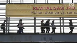 Pejalan kaki melintas di JPO Jalan Sudirman yang dipasangkan Spanduk peringatan revitalisasi, Jakarta (6/11). Tiga JPO yang akan direvitalisasi JPO Bundaran Senayan, JPO Polda Metro Jaya, dan JPO di Stadion Utama GBK. (Liputan6.com/Immanuel Antonius)